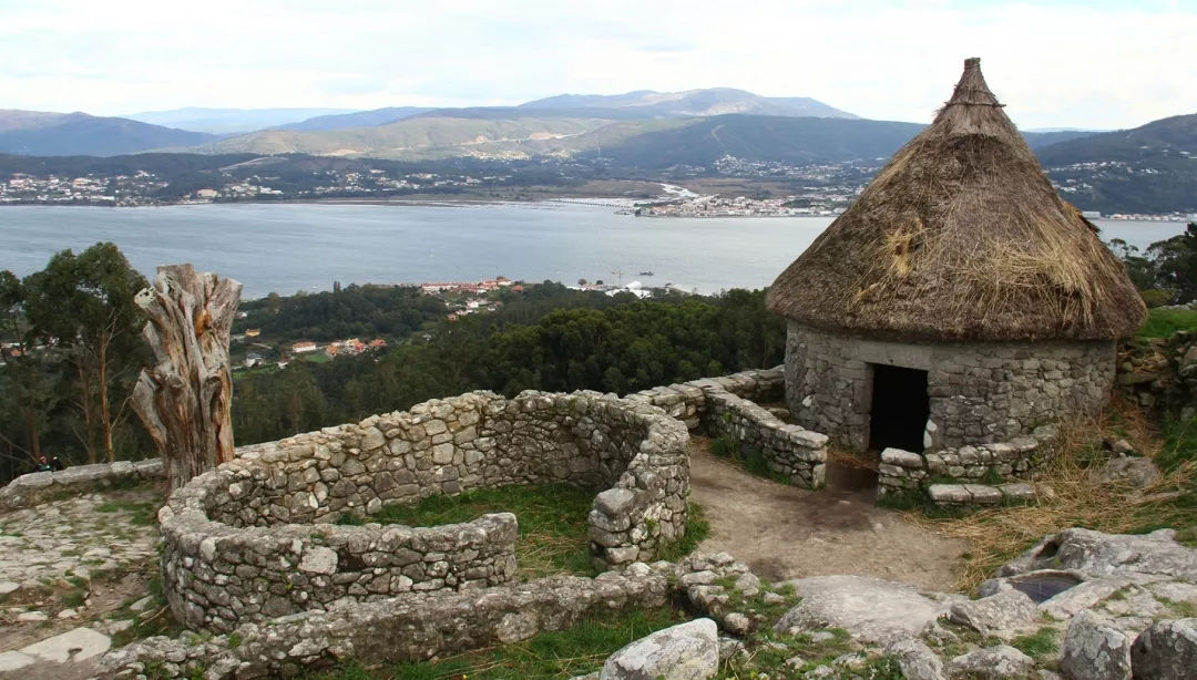 Panoramic view from Monte Santa Trega above A Guarda, Galicia, showing the Miño River meeting the Atlantic Ocean with ancient Celtic ruins in the foreground.